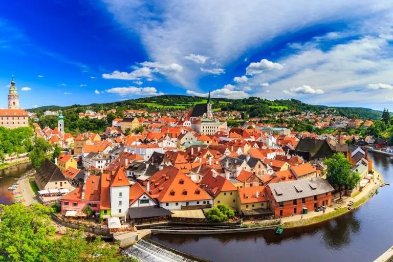 the Old Town of Cesky Krumlov seen from above with the Vltava River winding around and the tower of the Krumlov Castle peeking out on the left