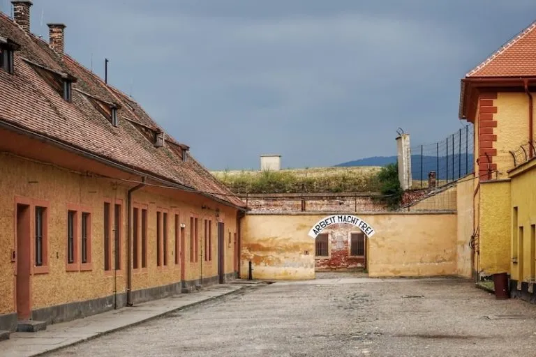 the main courtyard inside the former concentration camp in Terezin with a gate at the end with the sign "Arbeit Macht Frei" above it