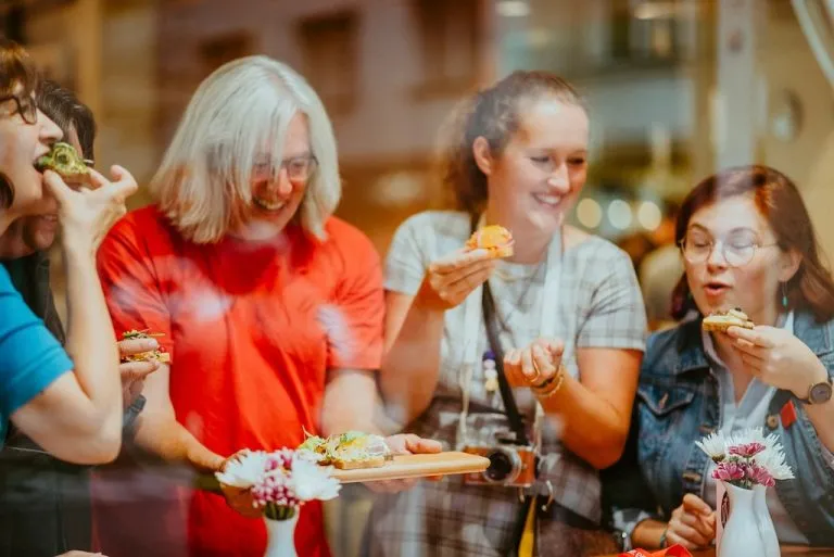 Your local tour guide is holding a platter with traditional Czech open-faced sandwiches and handing them out to his guests on a Prague food tour.