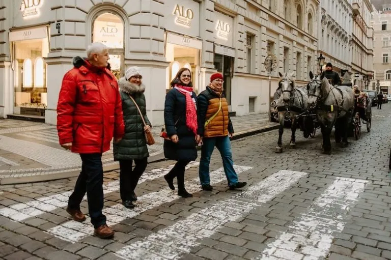 a tour guide leading a group of travelers across a cobblestone street in the center of Prague
