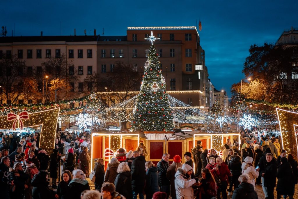 Evening view over a busy square filled with stalls and lights on a Prague Christmas market tour, capturing the magic of Christmas in Prague.