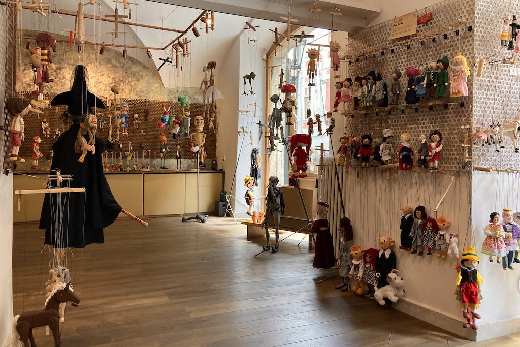 inside the Czech Marionettes shop - handmade wooden puppets hanging from the walls and the ceiling