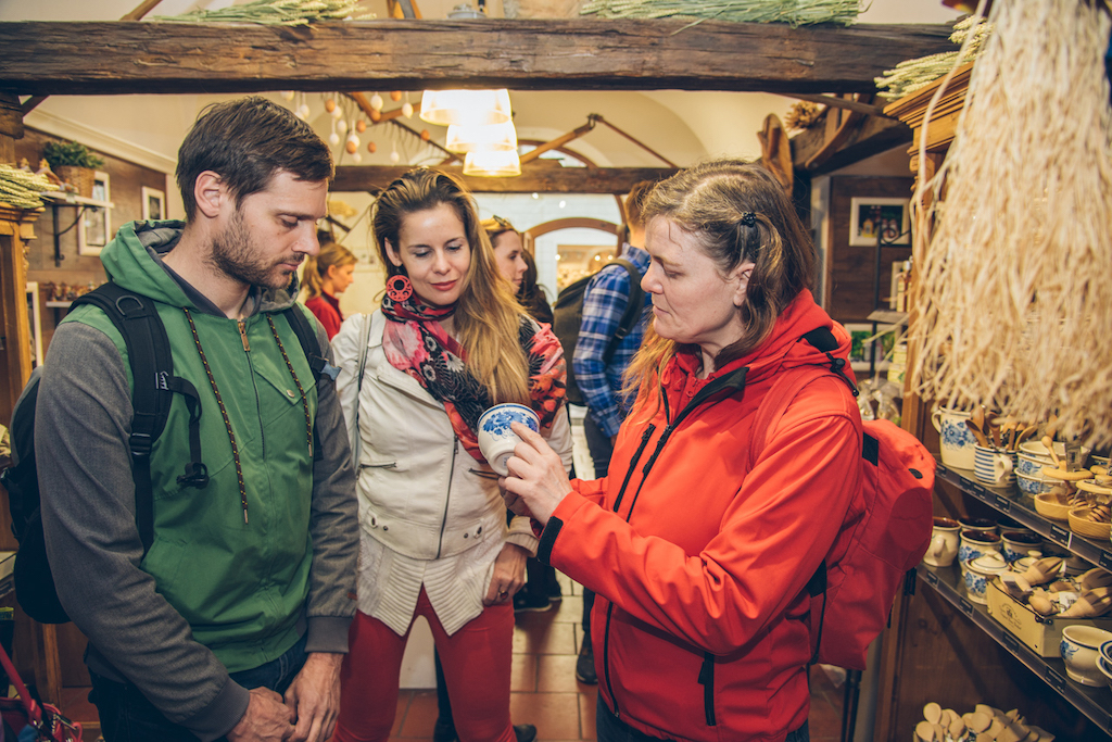 a tour guide showing a cup made of Czech porcelain with a traditional blue pattern to a group of guests on a guided tour in Prague