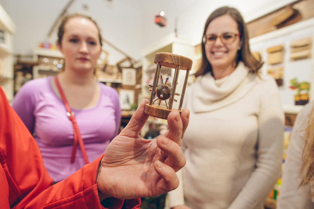 a person holding a traditional Czech brain teaser called "Jezek v kleci" - a hedgehog trapped in a wooden cage, trying to get out