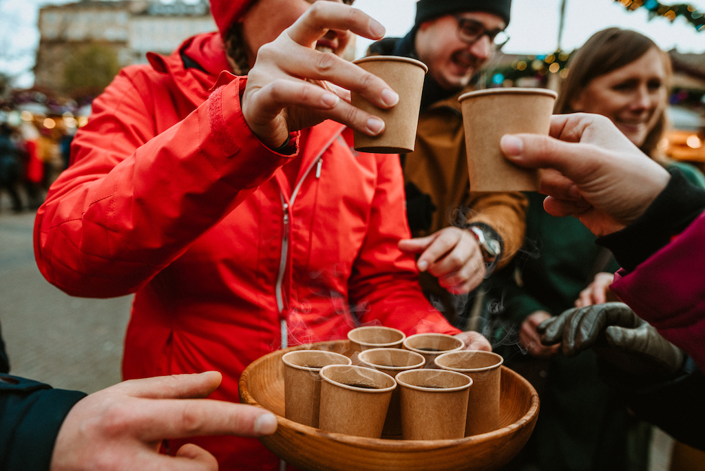 a tour guide raising a glass of hot drink and cheering together with tourists on a Prague Christmas Markets tour