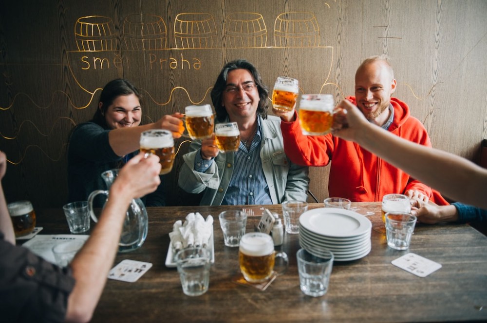 a group of tourists on a beer tour in Prague toasting with beer glasses in their hands in one of the Lokal restaurants