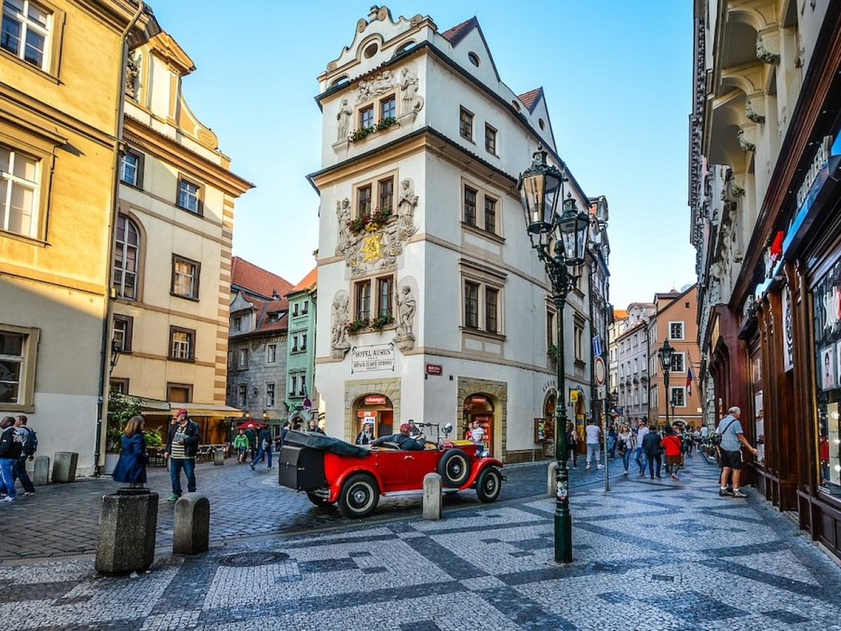 a street corner in the Old Town of Prague with a red vintage car in the foreground